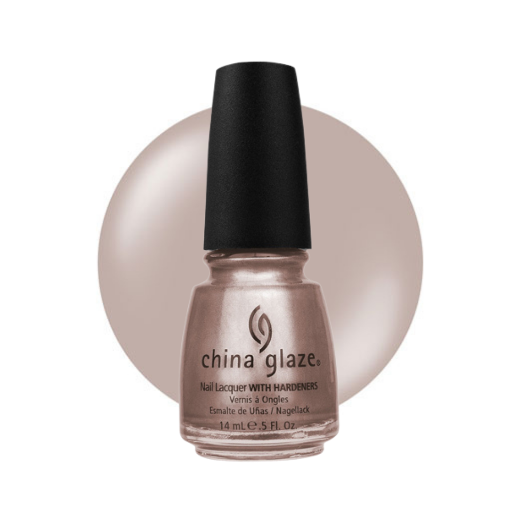 A bottle of China Glaze nail polish with a black cap, showing a shimmering champagne-beige polish, set against a matching beige circular background on a white studio backdrop.