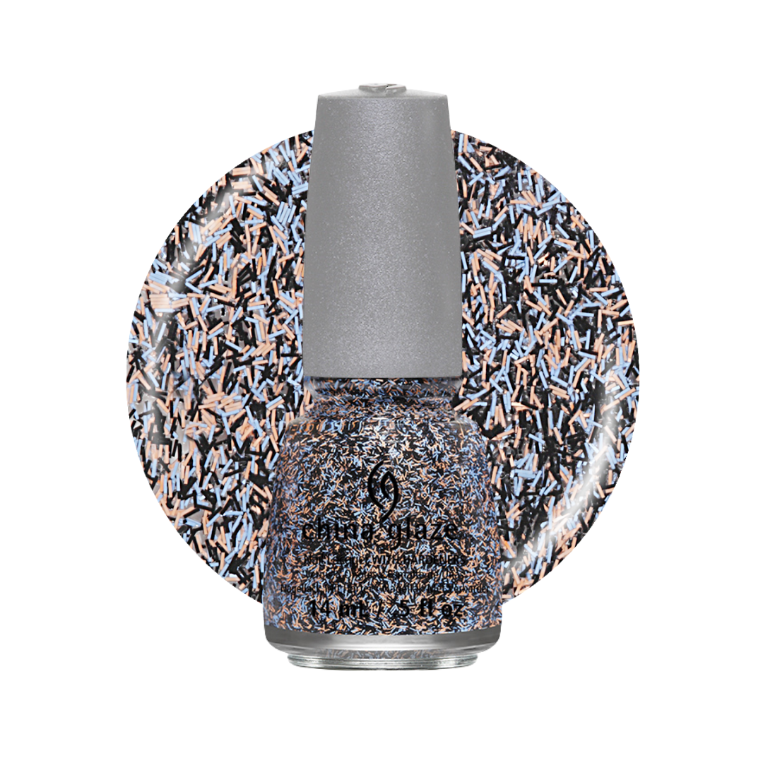 A bottle of nail polish with a silver cap, shown in front of a circular color swatch displaying a dense multicolor glitter pattern of black, blue, and peach-pink.