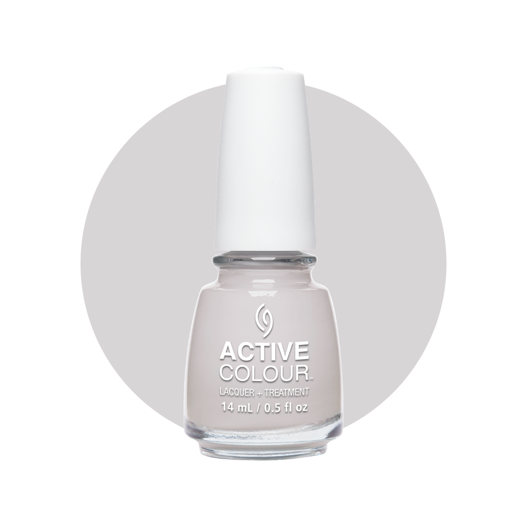 A bottle of Active Colour Lacquer + Treatment nail polish in a pale, light pinkish-gray shade, shown against a white background with a large light gray circle behind the bottle.