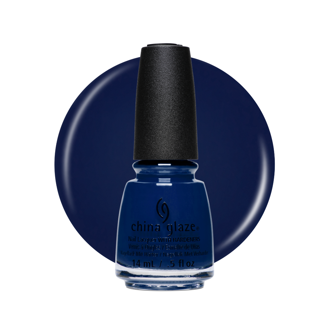 A bottle of China Glaze nail polish in a deep navy blue shade, set against a matching navy blue circular background on a white studio backdrop.