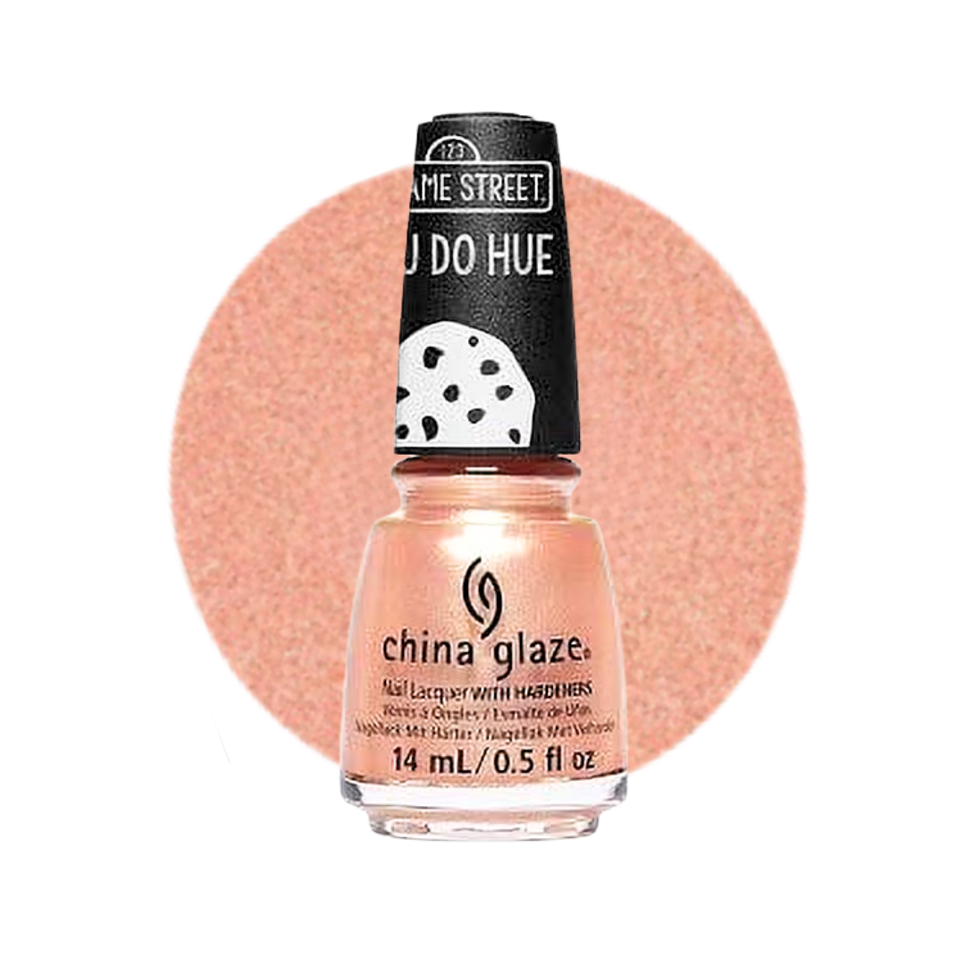 A bottle of China Glaze nail polish from their 'Sesame Street' collection, featuring a peachy pink glitter polish and a black cap with white text and a polka dot cookie graphic, set against a matching peachy pink circular swatch on a white background.