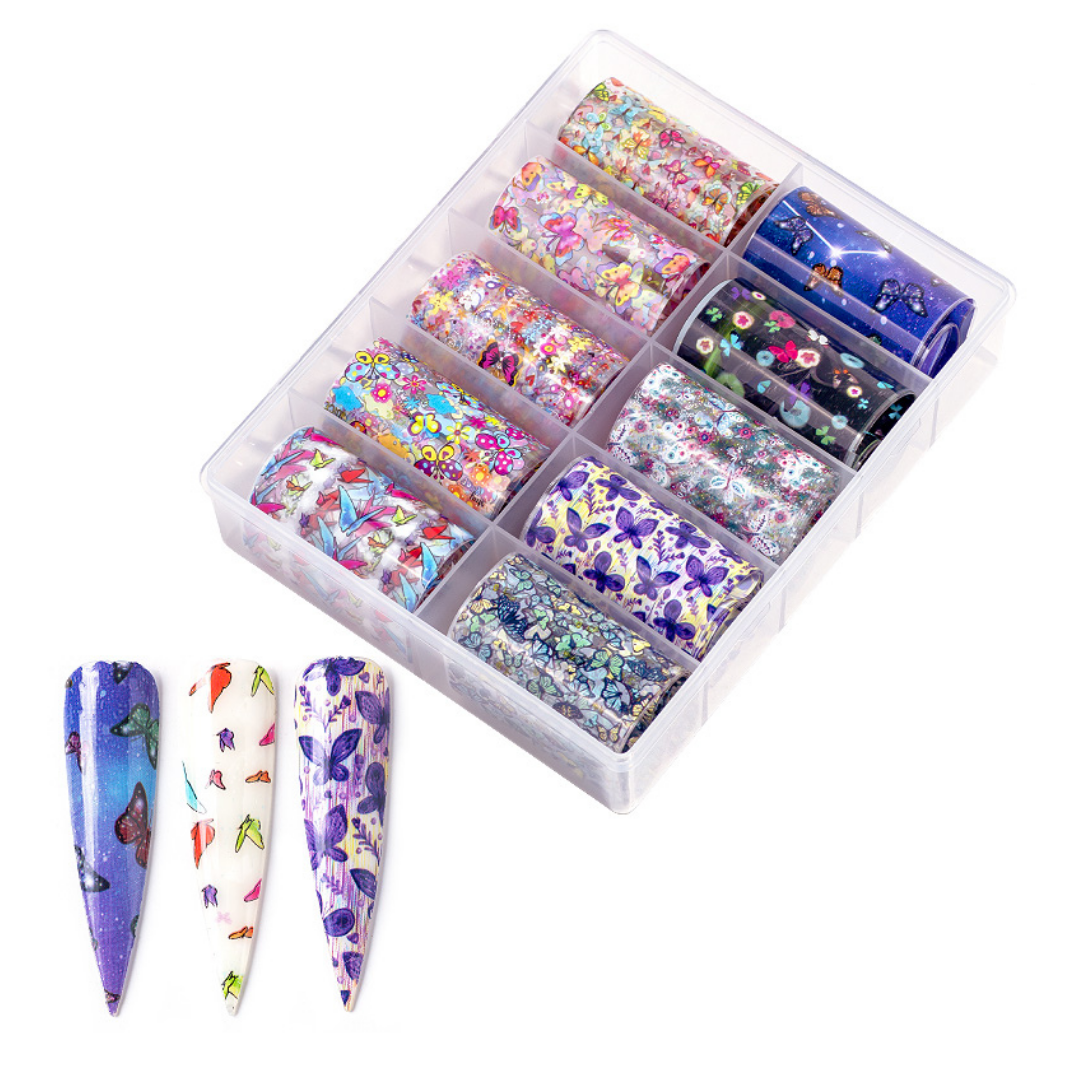 A clear plastic organizer tray holding multiple rolls of decorative nail art foil in assorted floral, butterfly, and glitter patterns, with three sample stiletto nails shown in front displaying matching multicolor designs on a white background.