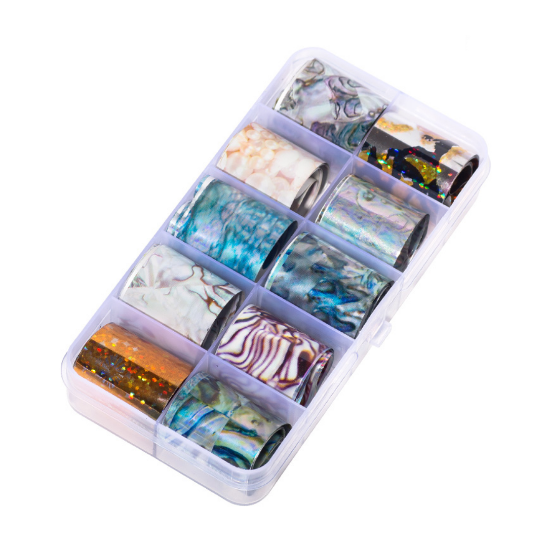 A clear plastic organizer box containing multiple rolls of decorative nail art foil with various marbled, metallic, and glitter patterns, shown on a plain white background.
