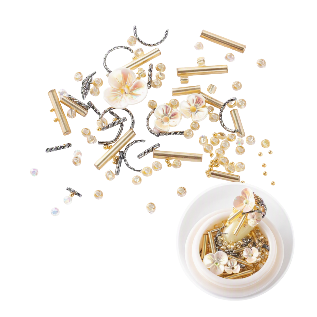 Gold and silver 3D Nail Art beads, flower embellishments, and metallic tubes scattered on a white background, with a small white bowl at the bottom right containing a decorated floral bead piece.