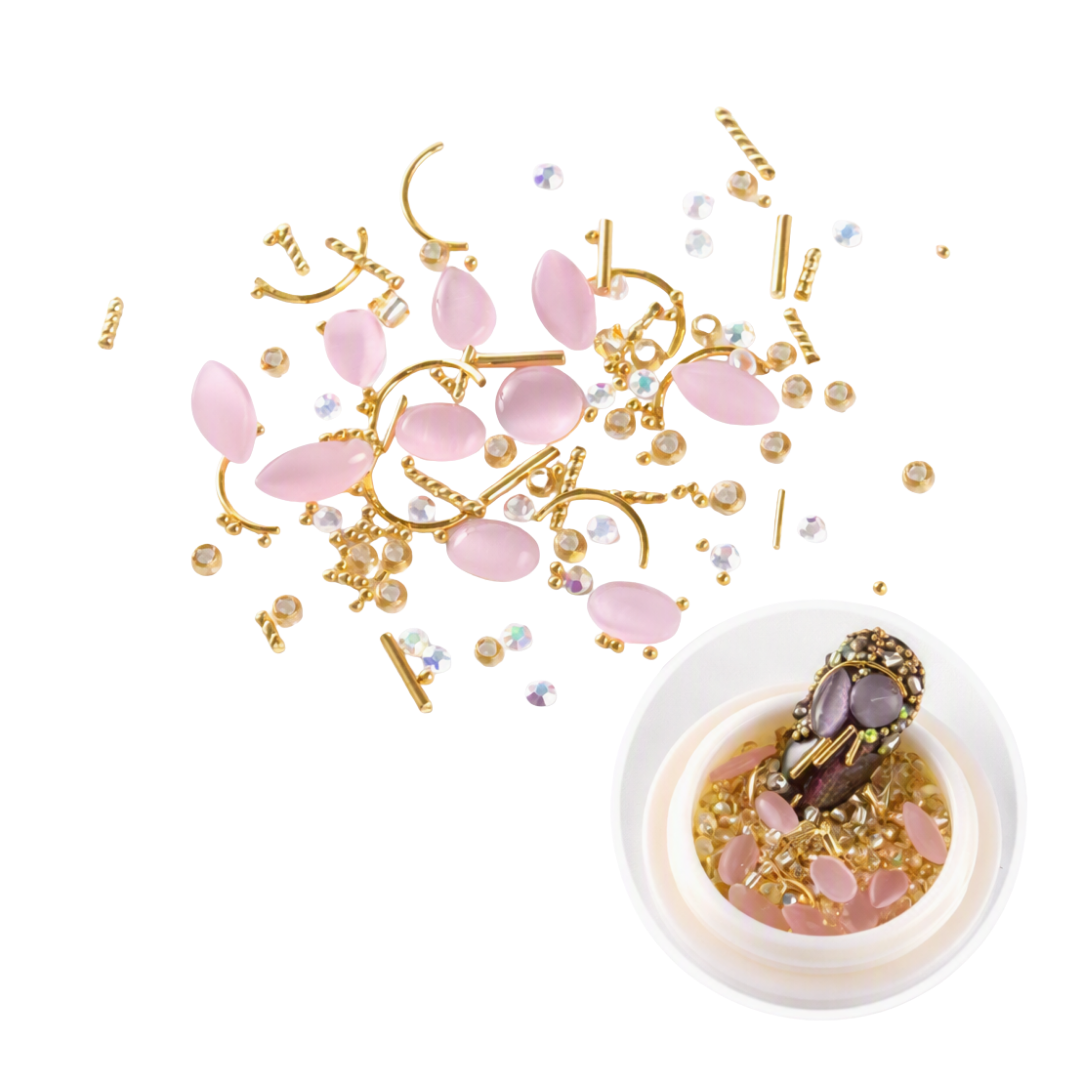 Pink rose quartz nail art beads and gold metal wire frames scattered on a white background, with a small white bowl containing a decorated nail tip in the lower right corner.