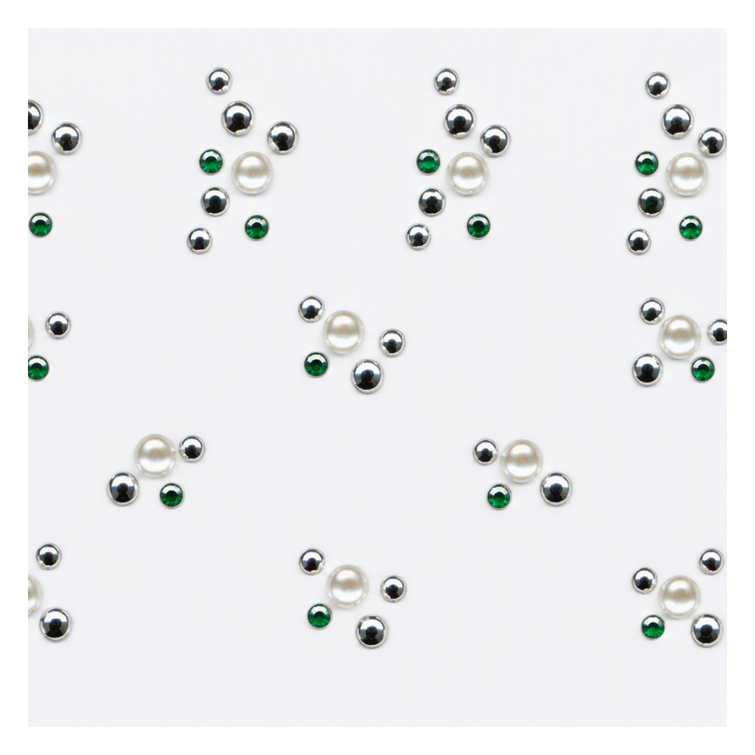 A repeating pattern of small decorative nail art bead clusters on a white background, featuring faux pearls, metallic silver beads, and green faceted beads.