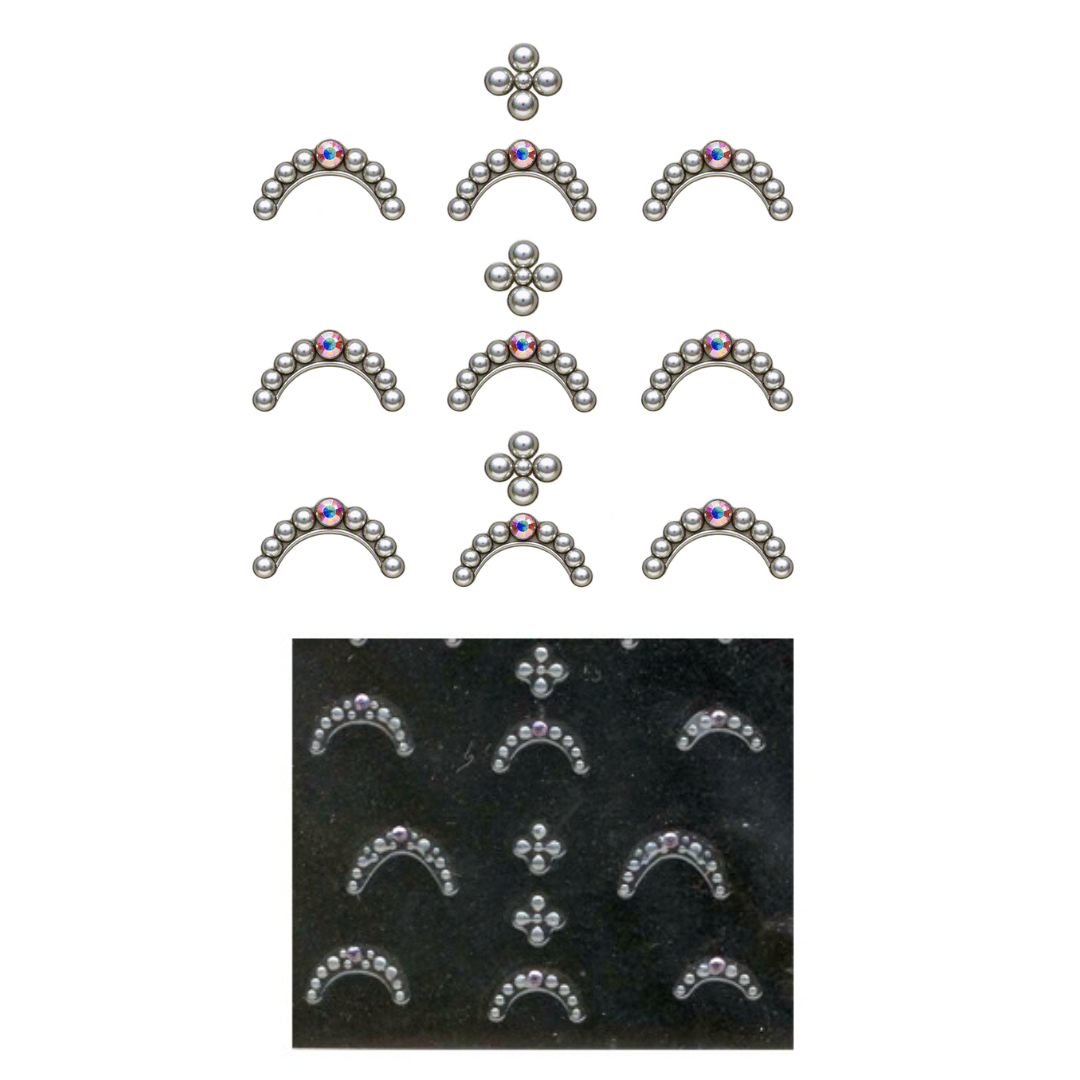 A set of silver-toned metal jewelry nail art, including several small arched pieces with tiny blue and purple stones and three clover-shaped pieces, shown above a black tray holding matching molded or stamped pieces.