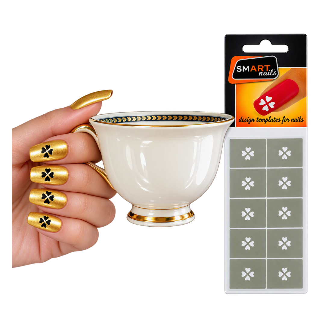 A hand with gold coffin-shaped nails decorated with black clover motifs holds a white teacup with gold trim, next to a package of Smart Nails design templates for nails.