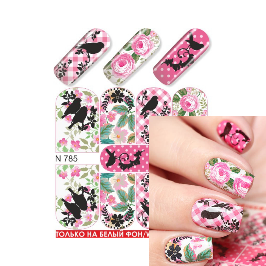 Nail art water slider sheet with pink roses, black birds, green leaves, and plaid patterns, shown alongside a hand displaying the finished manicure. The image includes text 'N 785' and a red note indicating use on white backgrounds.
