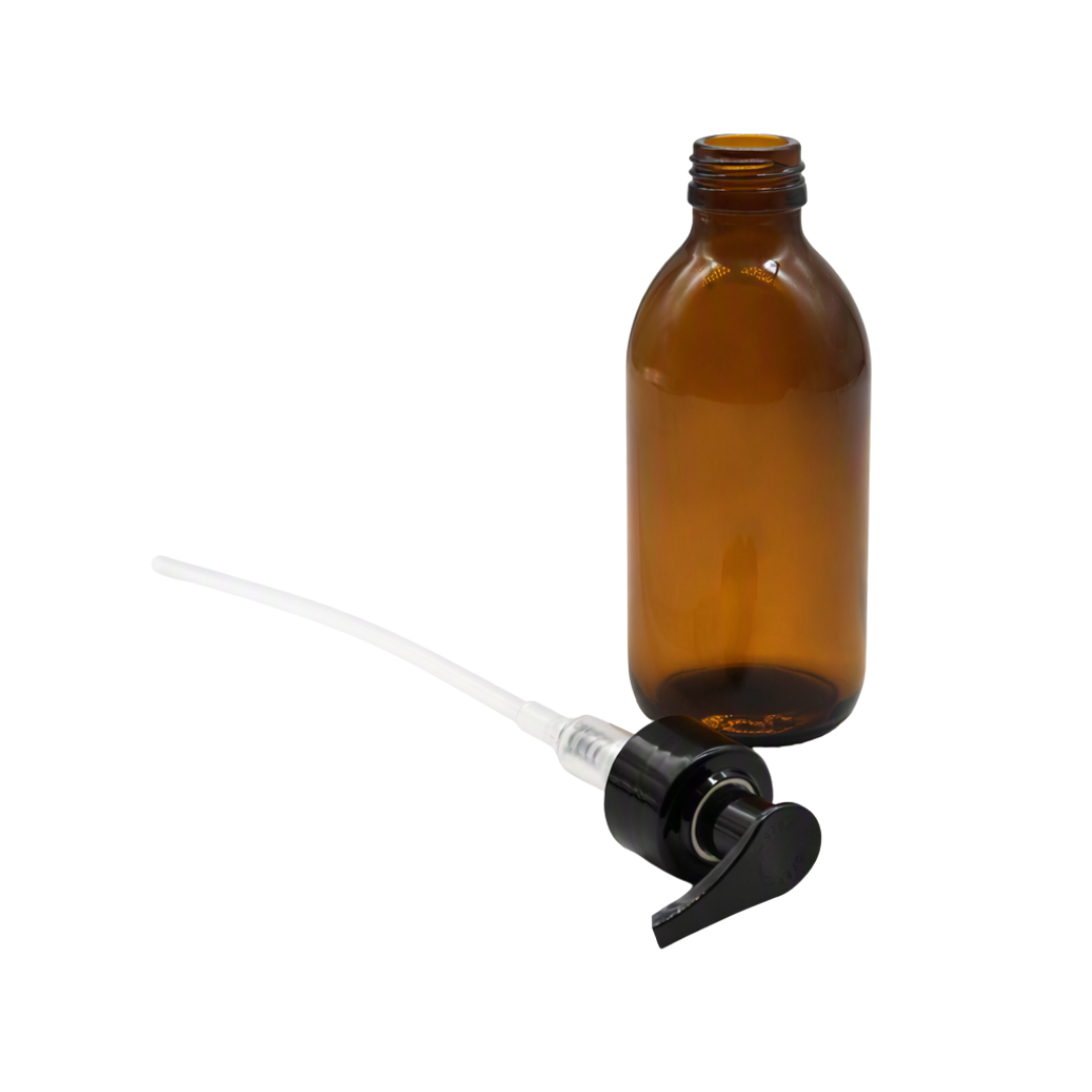 An empty amber glass bottle with a black and clear plastic pump dispenser shown next to it on a plain white background.