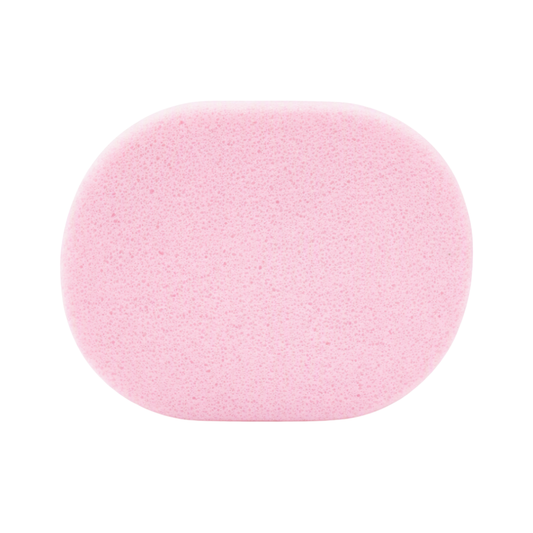 A light pink face wash sponge with a textured, porous surface, shown from a top-down view on a solid white background.