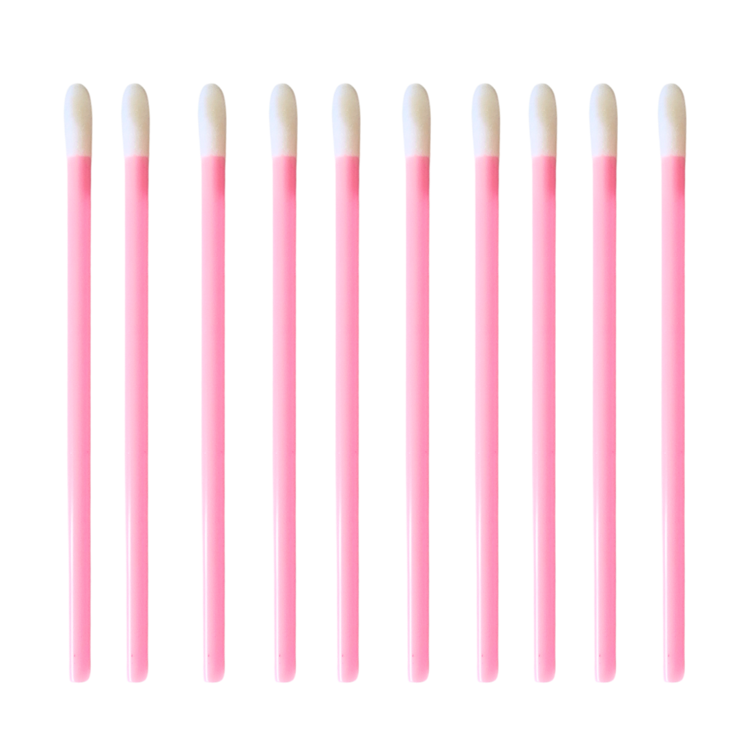 Ten pink lip gloss and lipstick swab sticks with white tips, arranged in a neat horizontal row on a solid white background.