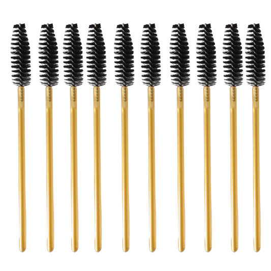 Ten gold spoolie-style eyebrow brushes with black bristles, arranged in a row on a plain white background.