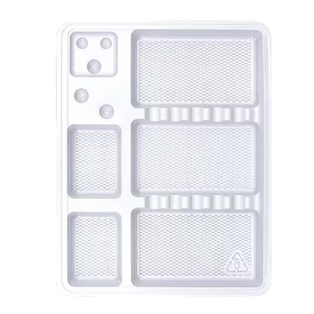 A clear plastic multi-compartment tray with textured rectangular sections, circular inserts, and a small triangular symbol near the bottom right, shown on a white background.