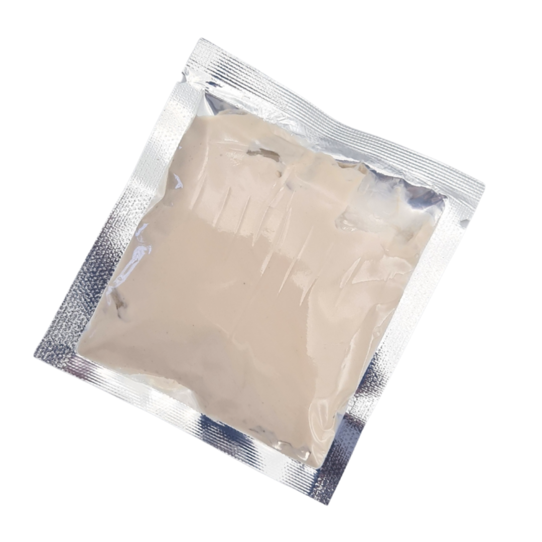 A square chocolate cocoa full body mud mask cream sealed in a transparent silver foil pouch, shown on a plain white background.