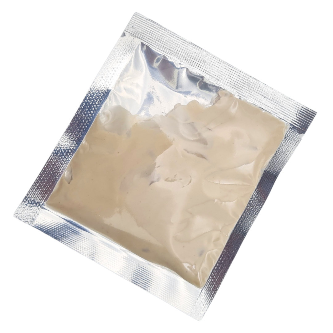 A square silver foil packet containing a beige hand and foot cream mask, shown on a plain white background.