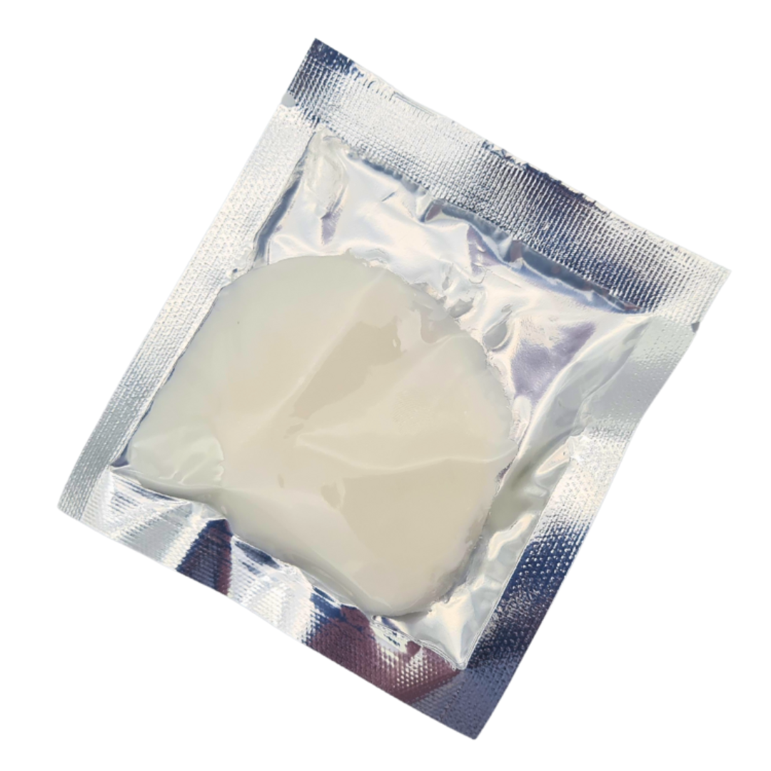 A single-use treatment of warm citrus massage cream for hands and feet, sealed inside a reflective silver foil packet, shown on a plain white background.