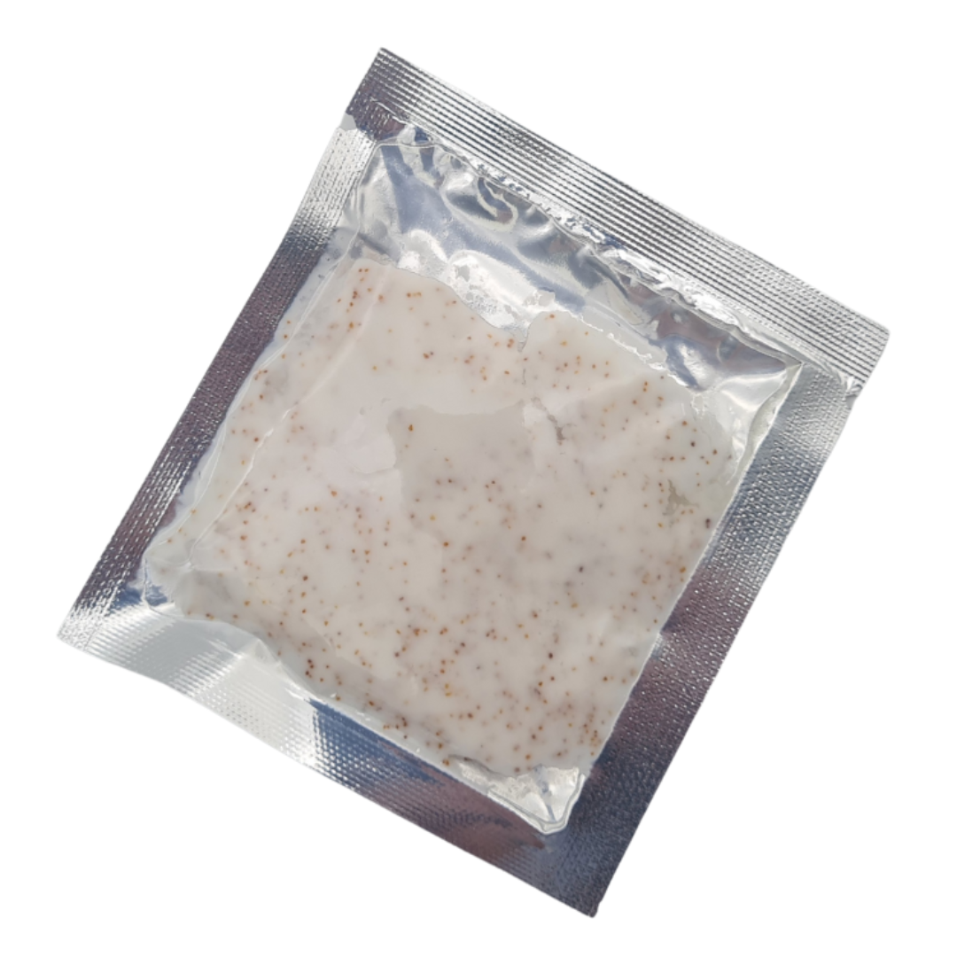 A square clear plastic pouch containing apricot kernel foot scrub, sealed in a silver metallic foil bag and photographed on a plain white background.