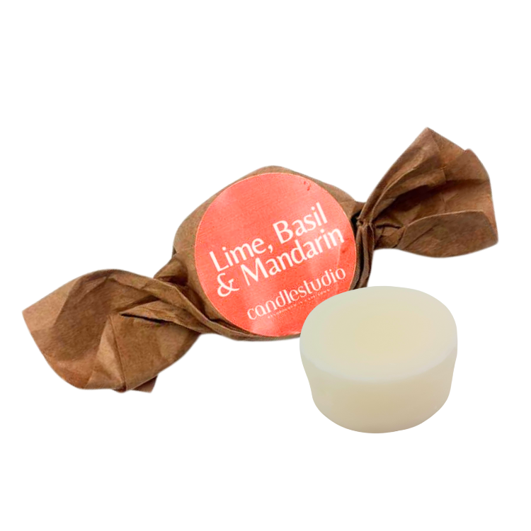 White candle in brown paper wrapper with 'Lime, Basil & Mandarin' label on a white background