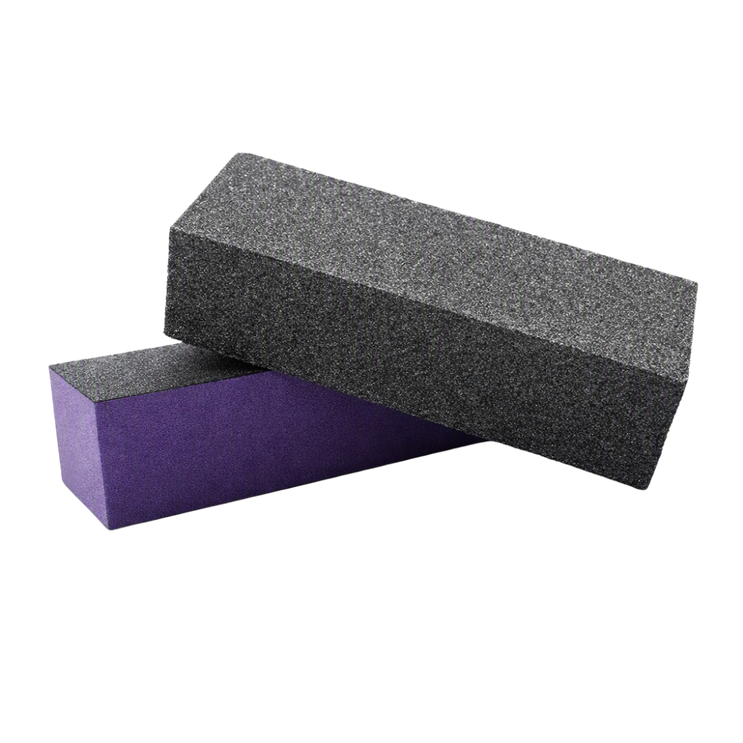 Two rectangular nail files or sanding blocks stacked, with the top block showing a black textured abrasive side and the bottom block showing a purple side, on a plain white background.