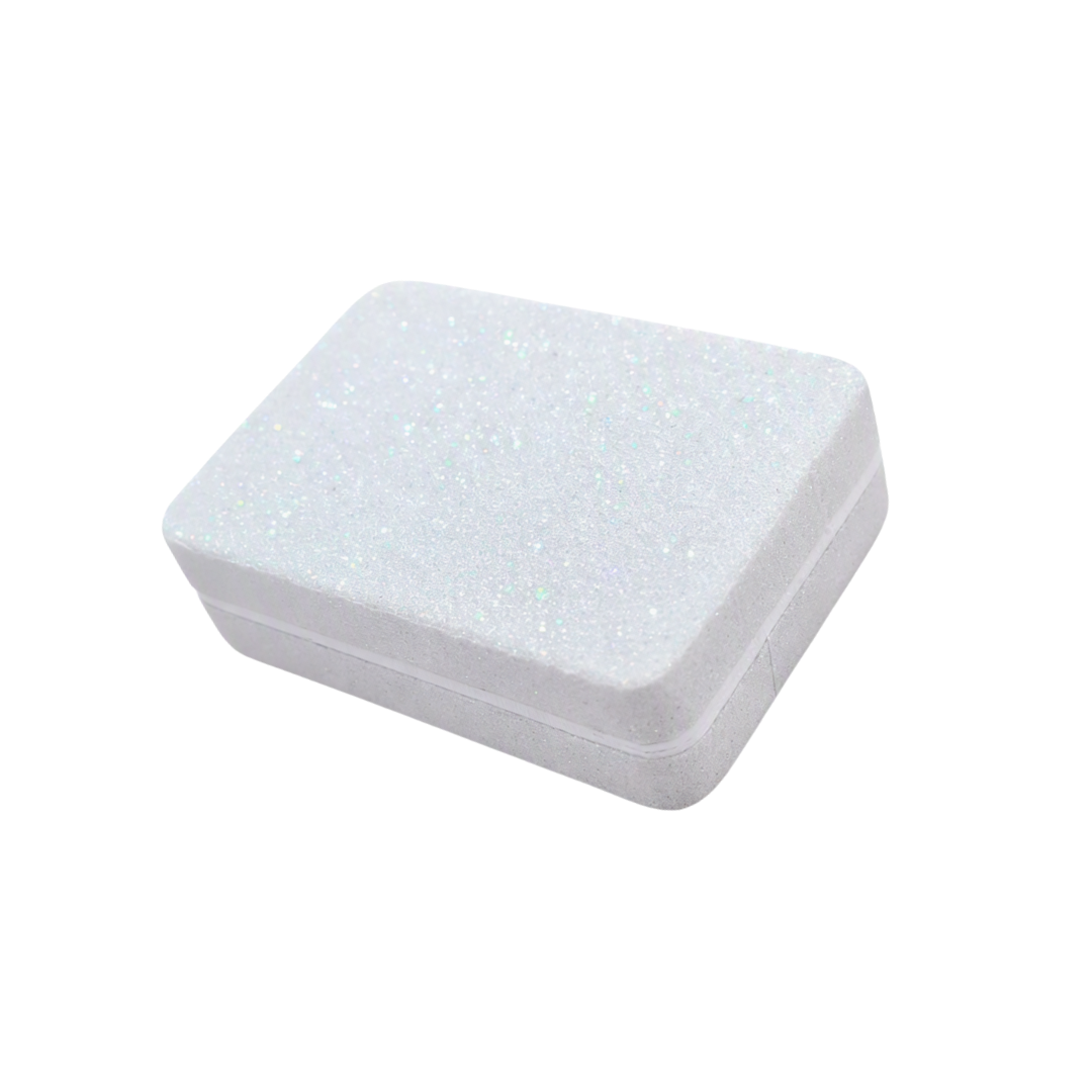 A small rectangular white foam nail sanding block with rounded corners and a subtle glittery texture, shown on a plain white background.