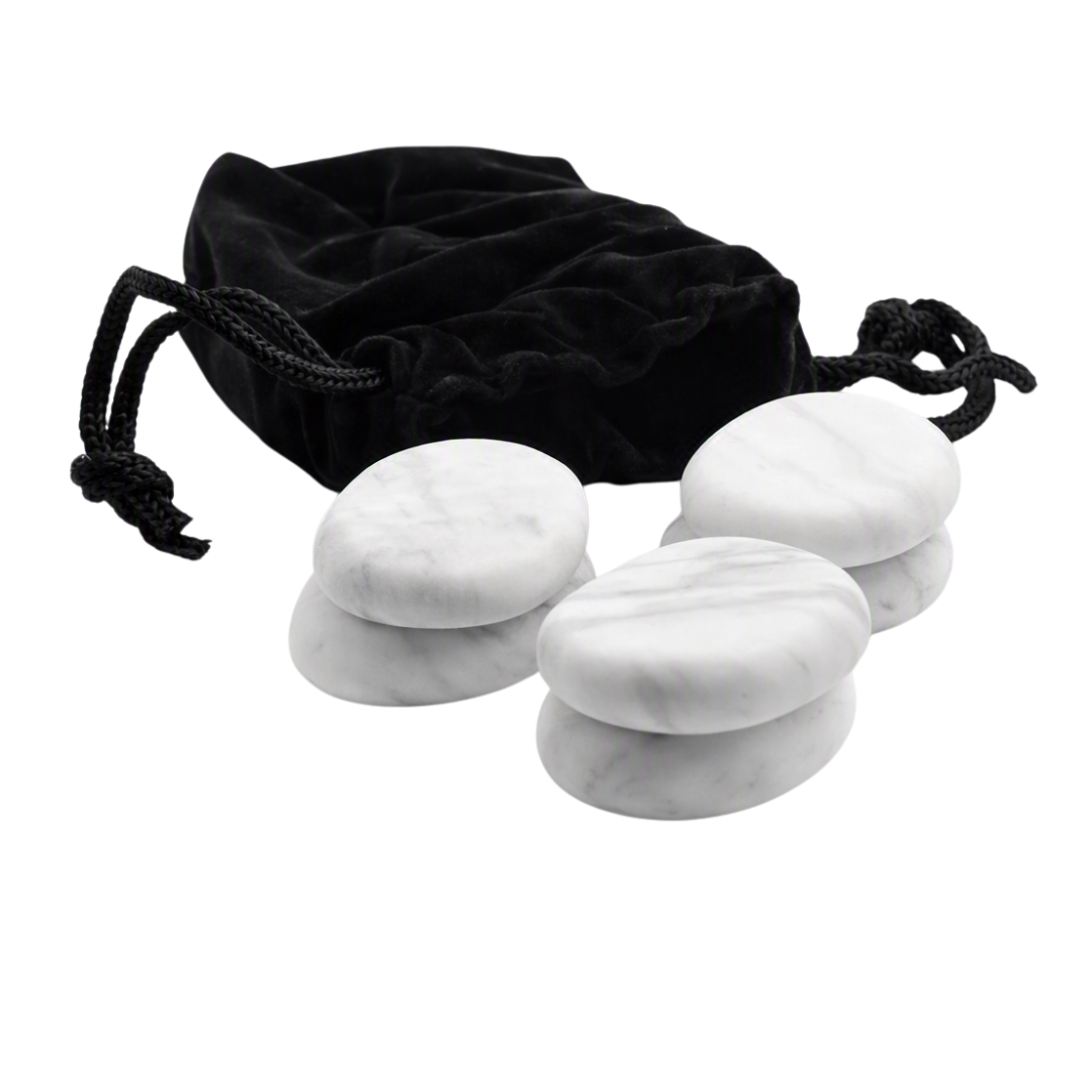 Six white marble massage stones arranged in front of a black velvet drawstring pouch on a plain white background.