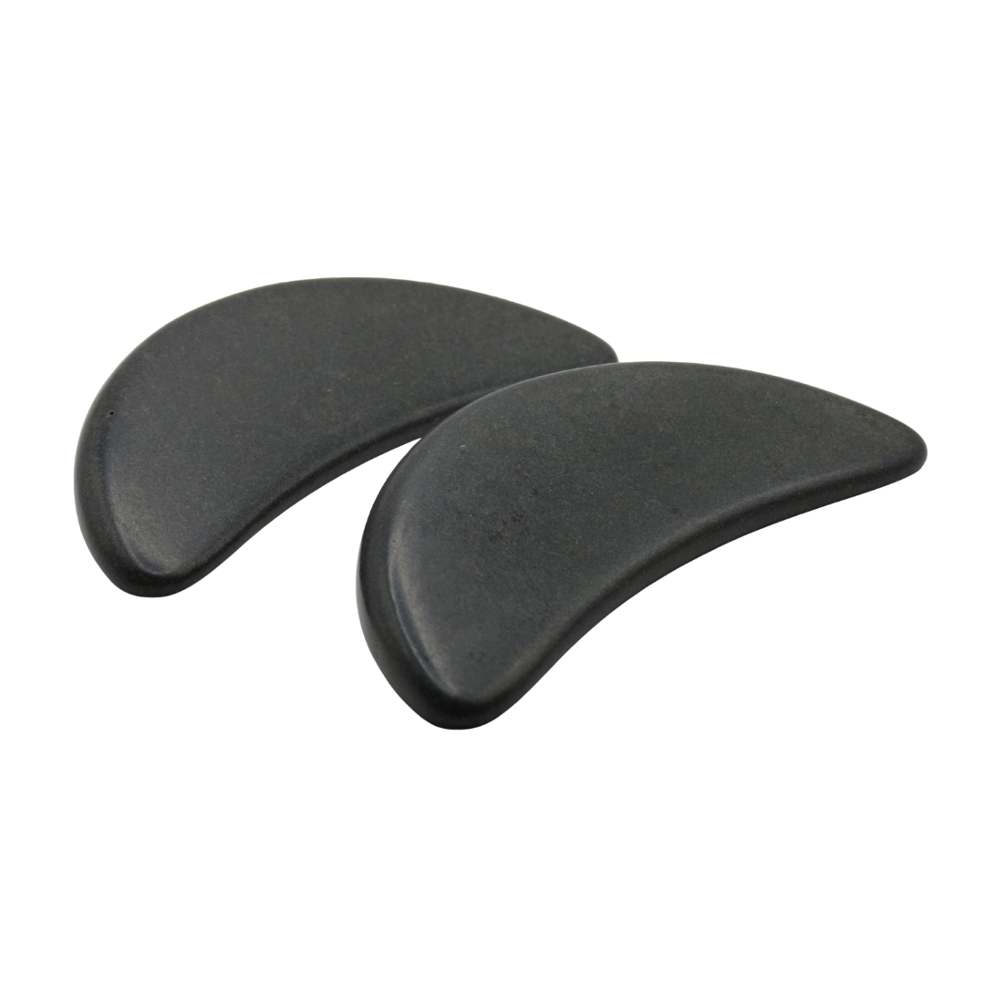 Two black crescent-shaped basalt massage stones shown side by side on a plain white background.