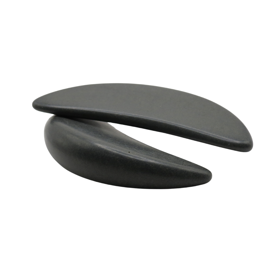 Two black crescent-shaped basalt massage stones shown side by side on a plain white background.