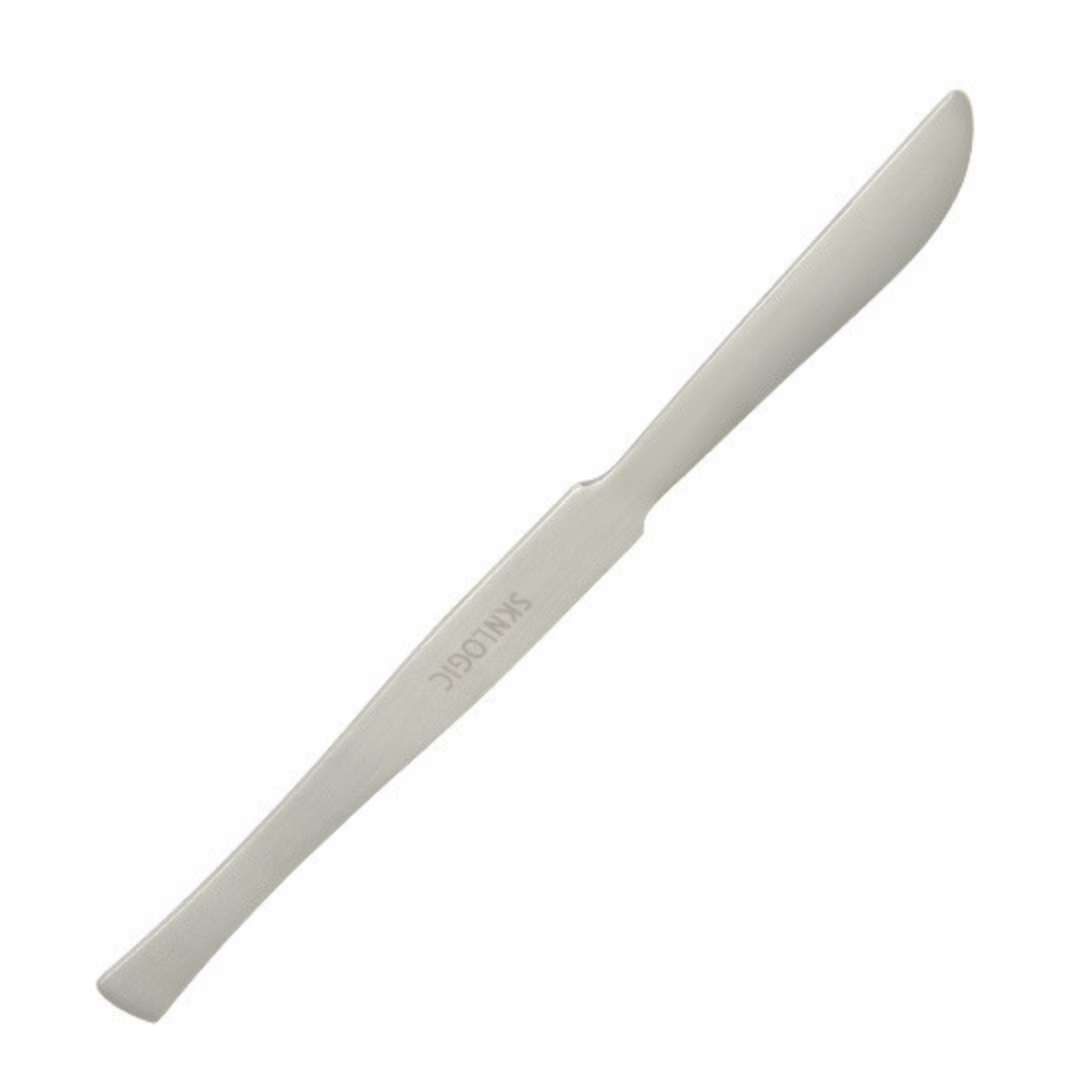 A single white metal knife blade or spatula-like pedicure tool for removing foot callus with the brand name 'SKNLOGIC printed on it, shown diagonally on a plain white background.