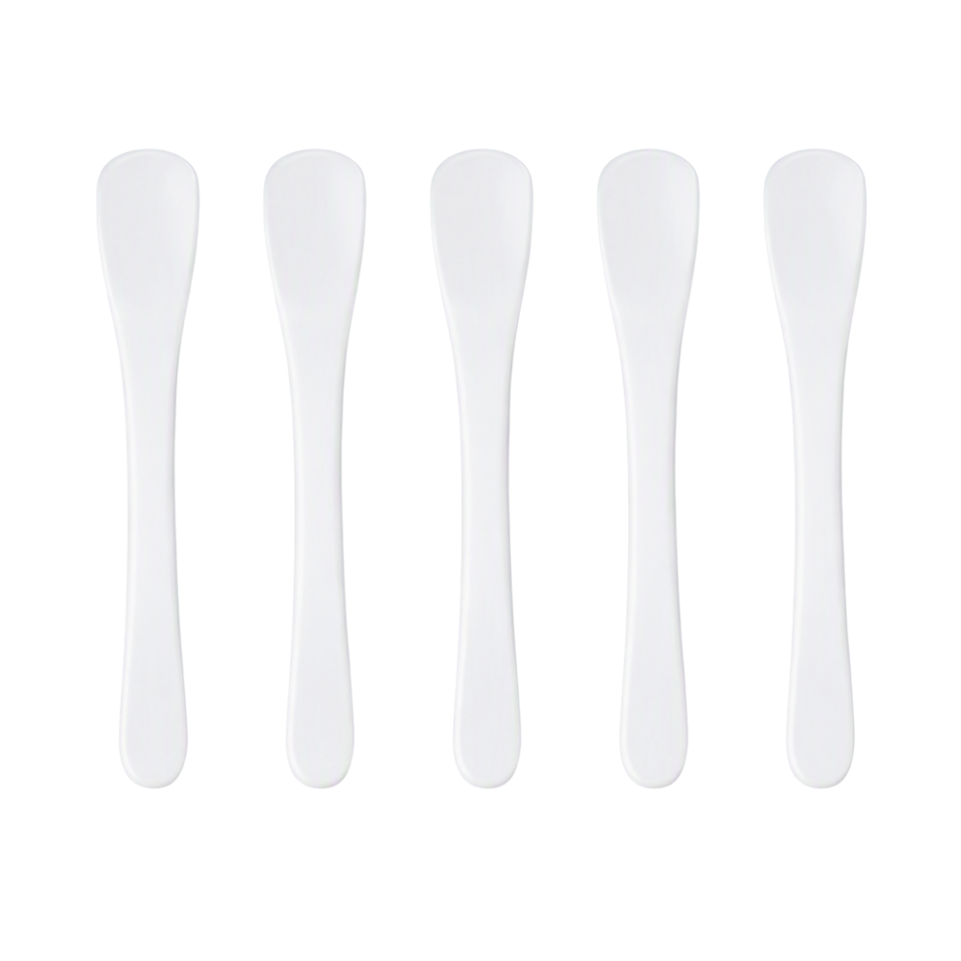 Five white plastic spatulas for creams arranged in a row on a plain white background.