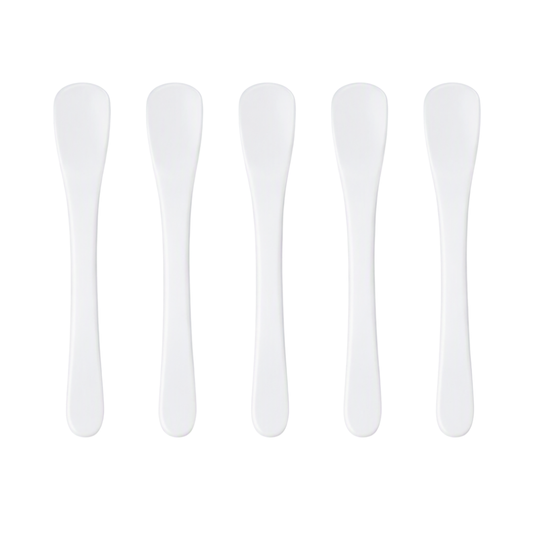 Five white plastic spatulas for creams arranged in a row on a plain white background.