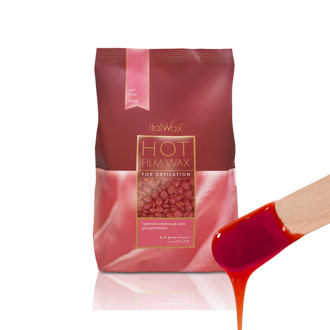 W311 Italwax Rose Film Wax | A bag of Italwax Rose Hot Film Wax for depilatory hair removal, shown next to a wooden spatula holding a glossy pool of the red wax.