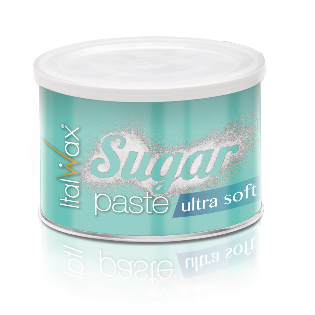 A round metal tin of ItalWax Sugar Paste in the 'ultra soft' shade, featuring a light teal label with white and blue text, a white lid, and a soft reflection on a white background.