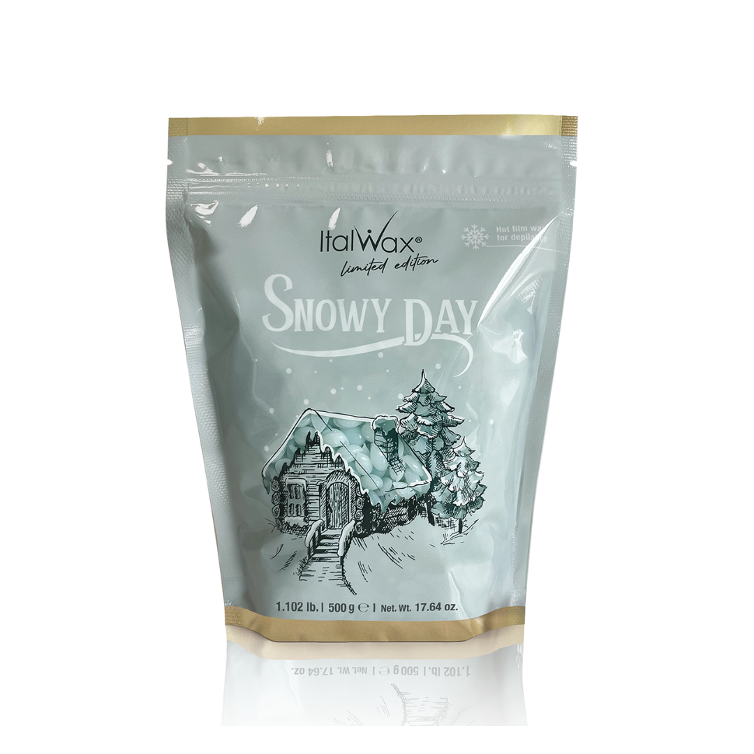 W501 Italwax Snowy Day Film Wax | A 500g bag of Italwax Limited Edition Snowy Day film wax, featuring a light gray-green background with a gold foil top and bottom, and an illustration of a snowy cabin and pine tree.
