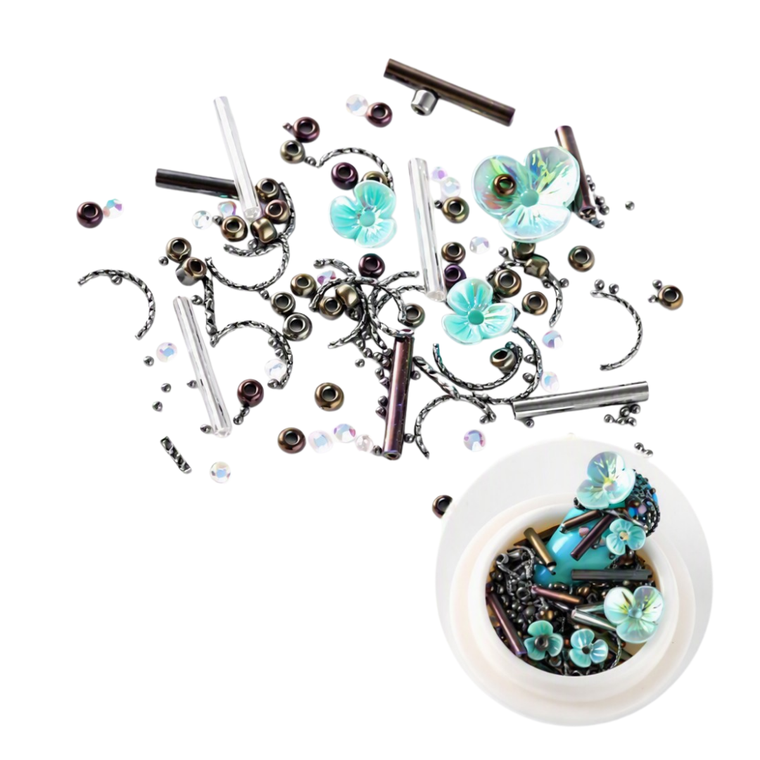 A collection of 3D Nail Art embellishments and beads scattered on a white background, with a small white dish in the lower right corner showing the contents. The embellishments include turquoise flower charms, iridescent beads, clear glass rods, and dark metallic components.