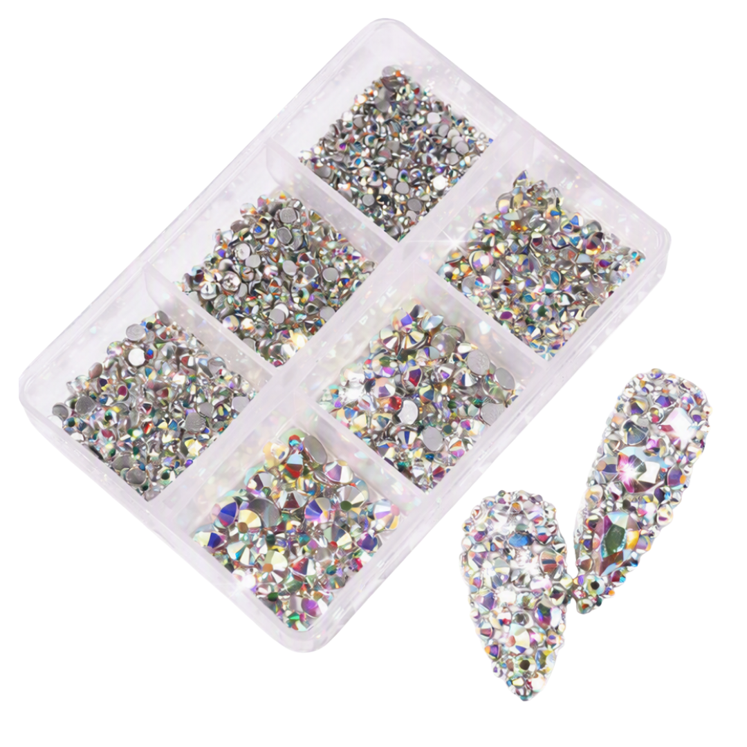 A clear plastic organizer tray filled with many small iridescent rhinestones, with two larger decorative nail tip pieces shown beside it on a white background.