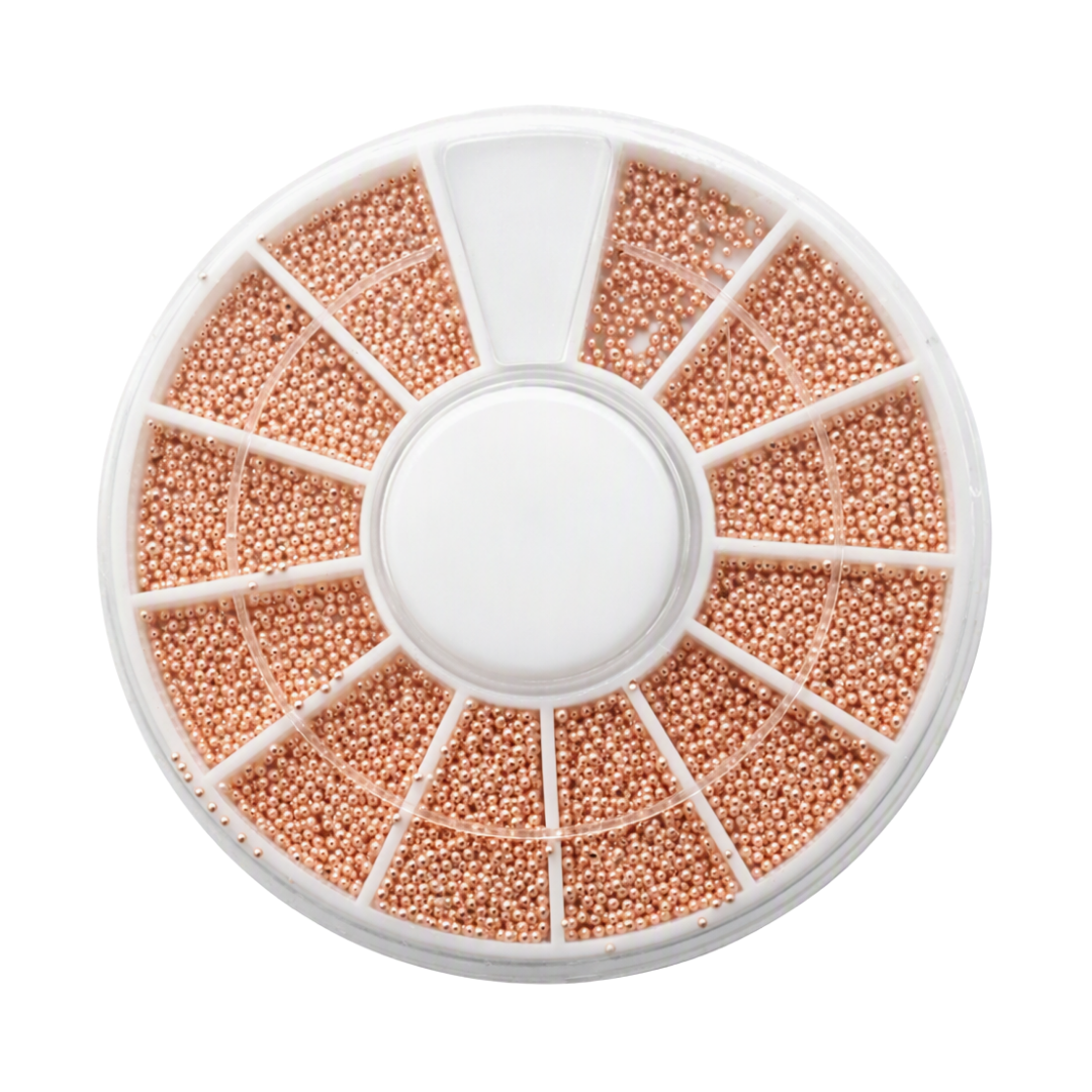 A circular white plastic compartment organizer filled with rose gold beads for decorative nail art pieces, on a plain white background.
