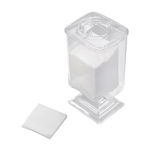 A clear plastic jar with a square base and lid, filled with white cotton pads, shown on a white background with a square white cotton facial wipe placed beside it.