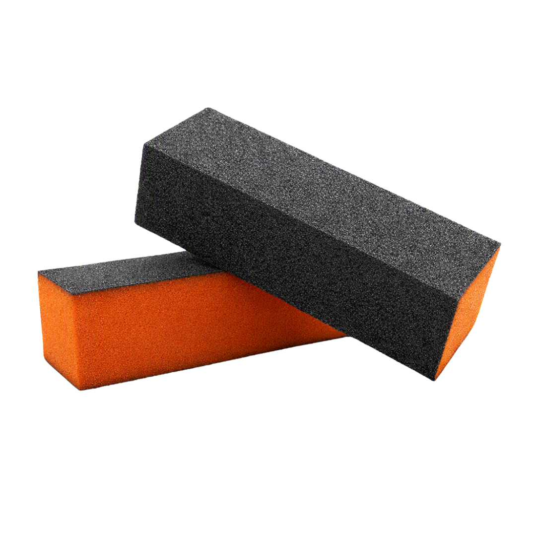 Two rectangular foam nail sanding blocks with a black abrasive top surface and bright orange sides, shown on a plain white background.