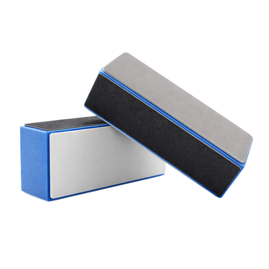 Two rectangular blue nail shiner blocks shown on a plain white background, one standing upright and one lying diagonally. The files have blue edges, a silver metal side, a black abrasive side, and a gray polishing side.