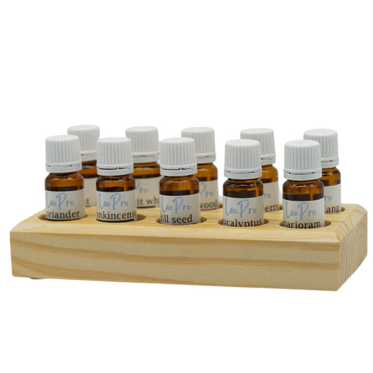 A wooden stand with multiple essential oil bottles arranged in it, each labeled with different essential oils such as Frankincense, Rosemary, and Lavender.