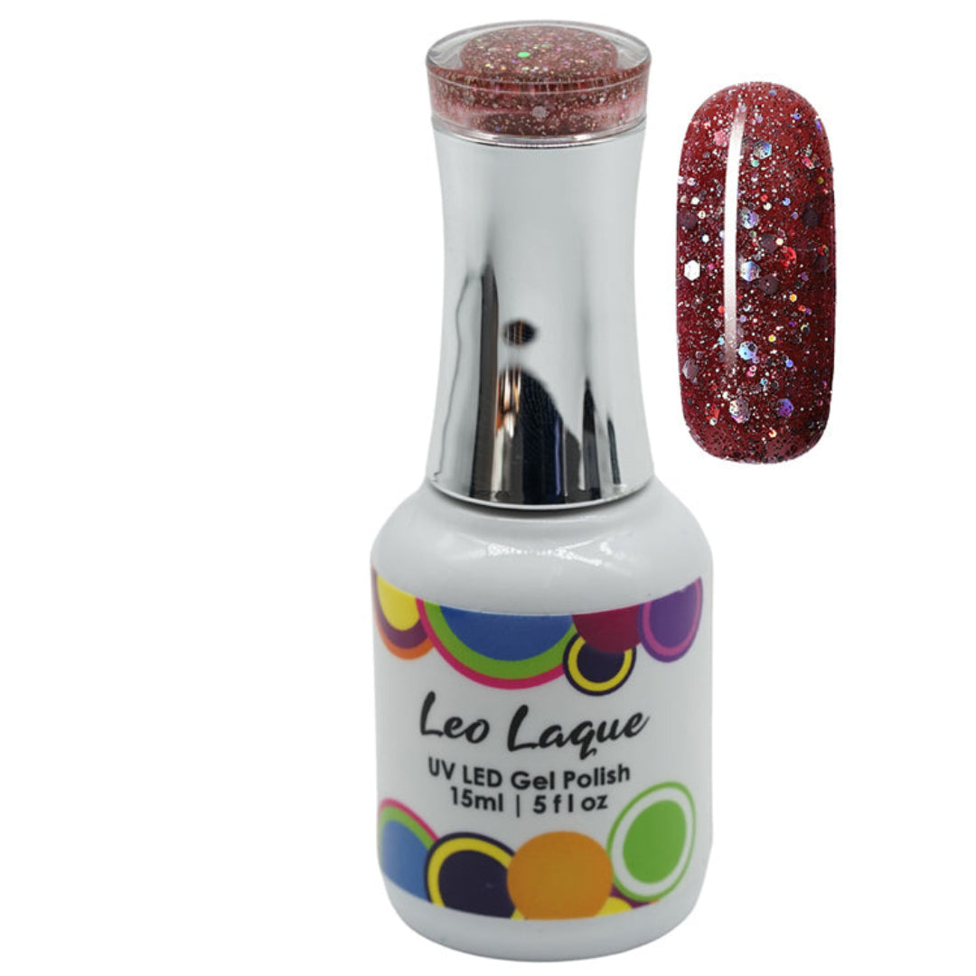 A bottle of Leo Laque UV LED gel polish with a silver cap and a multicolor circular label, shown next to a nail swatch displaying a sparkling deep red glitter polish.