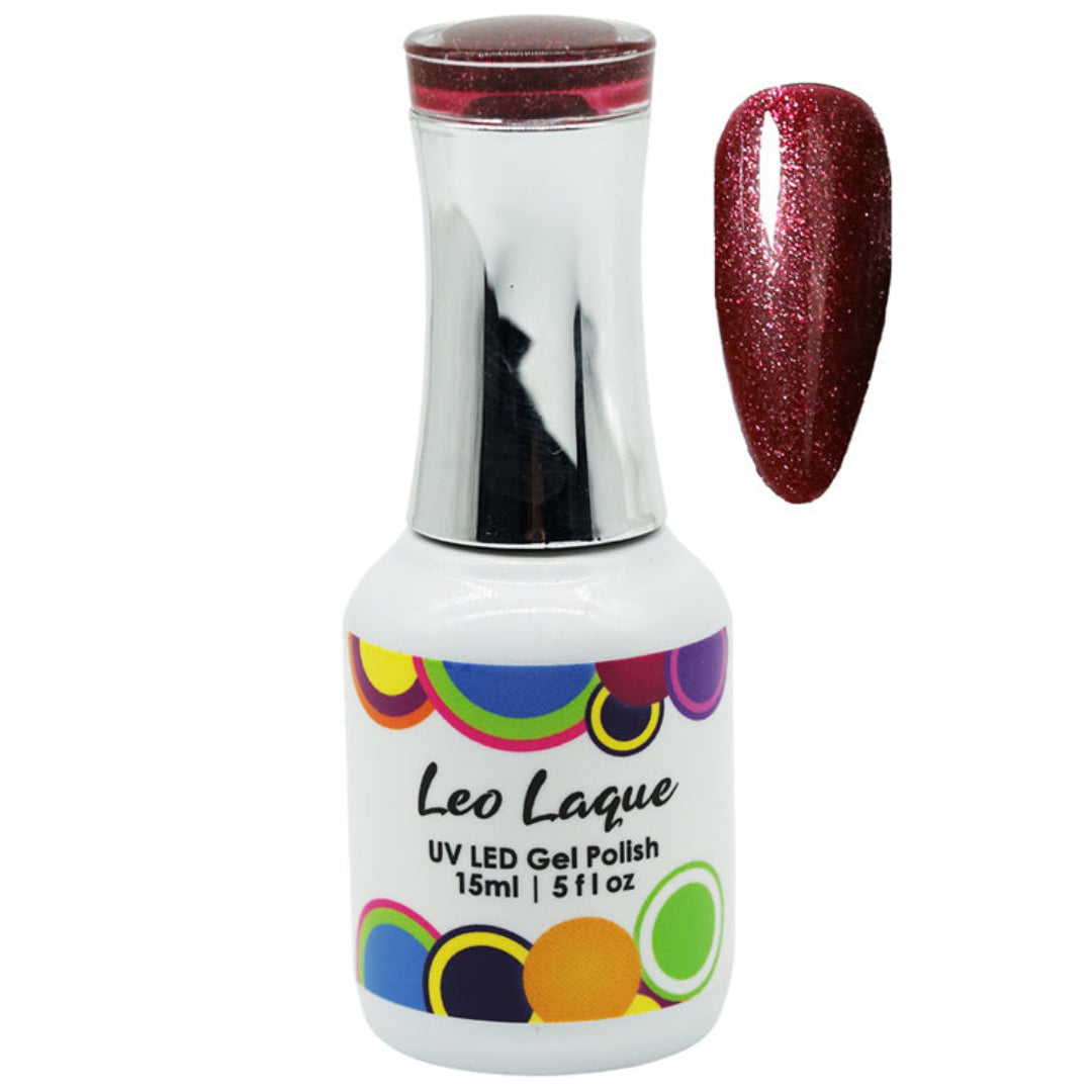 A bottle of Leo Laque UV LED gel polish with a metallic silver cap and a white label featuring colorful circles, shown next to a nail swatch displaying a sparkling deep red glitter polish.