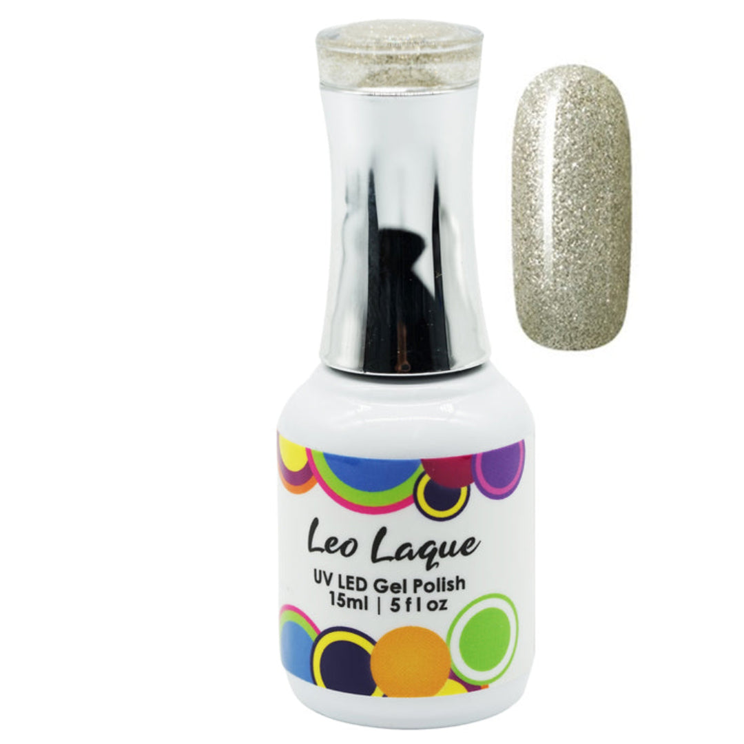 A bottle of Leo Laque UV LED Gel Polish with a silver cap, shown next to a nail swatch displaying a sparkling champagne gold glitter finish.