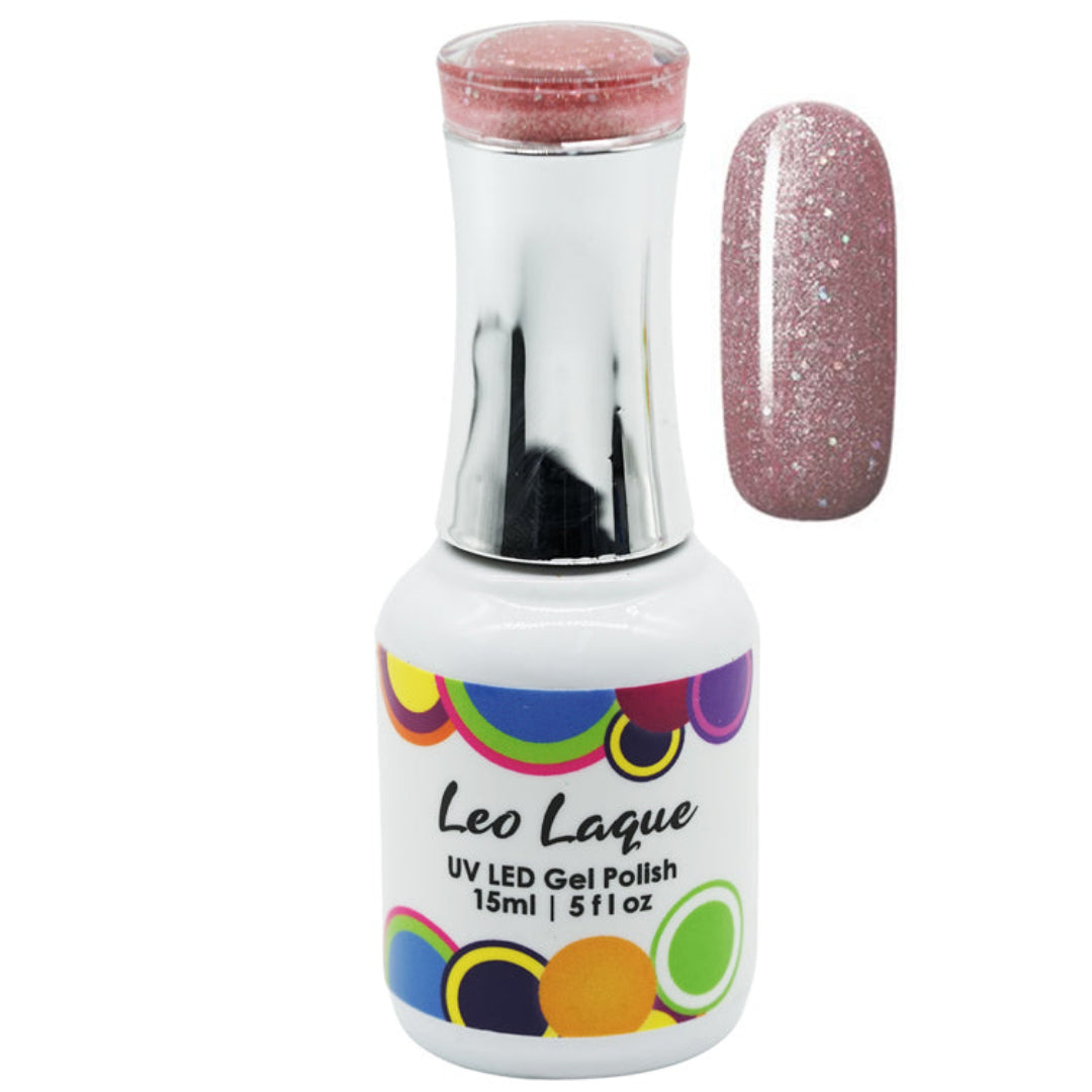 A bottle of Leo Laque UV LED gel nail polish with a silver cap and a white label featuring colorful circles, shown next to a vertical nail swatch displaying the glittery dusty rose pink polish.